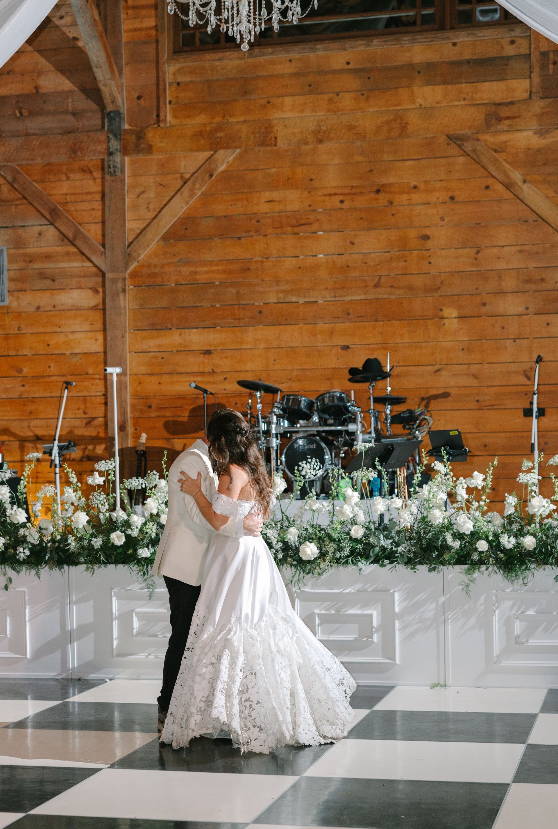 Bride and groom embracing on a checkered dance floor at a rustic wedding reception