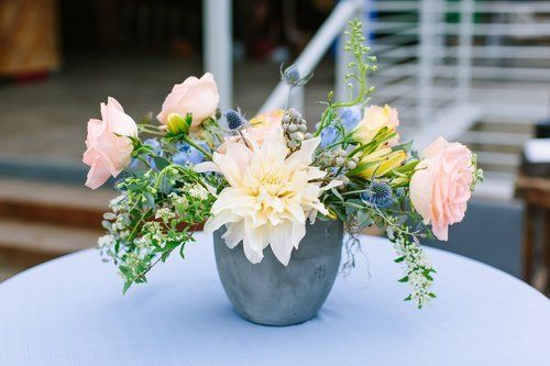 White and pink floral arrangement in a gray vase on a round table outdoors