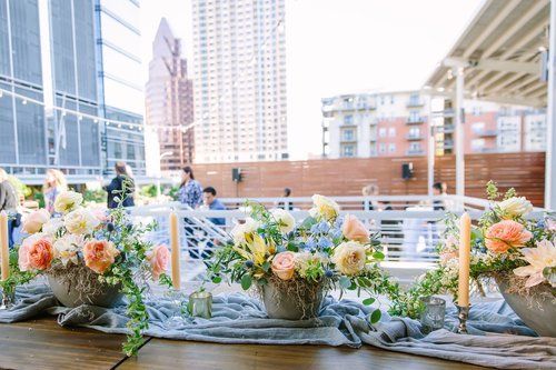 Flower arrangements on a table with a city skyline and rooftop railing in the background