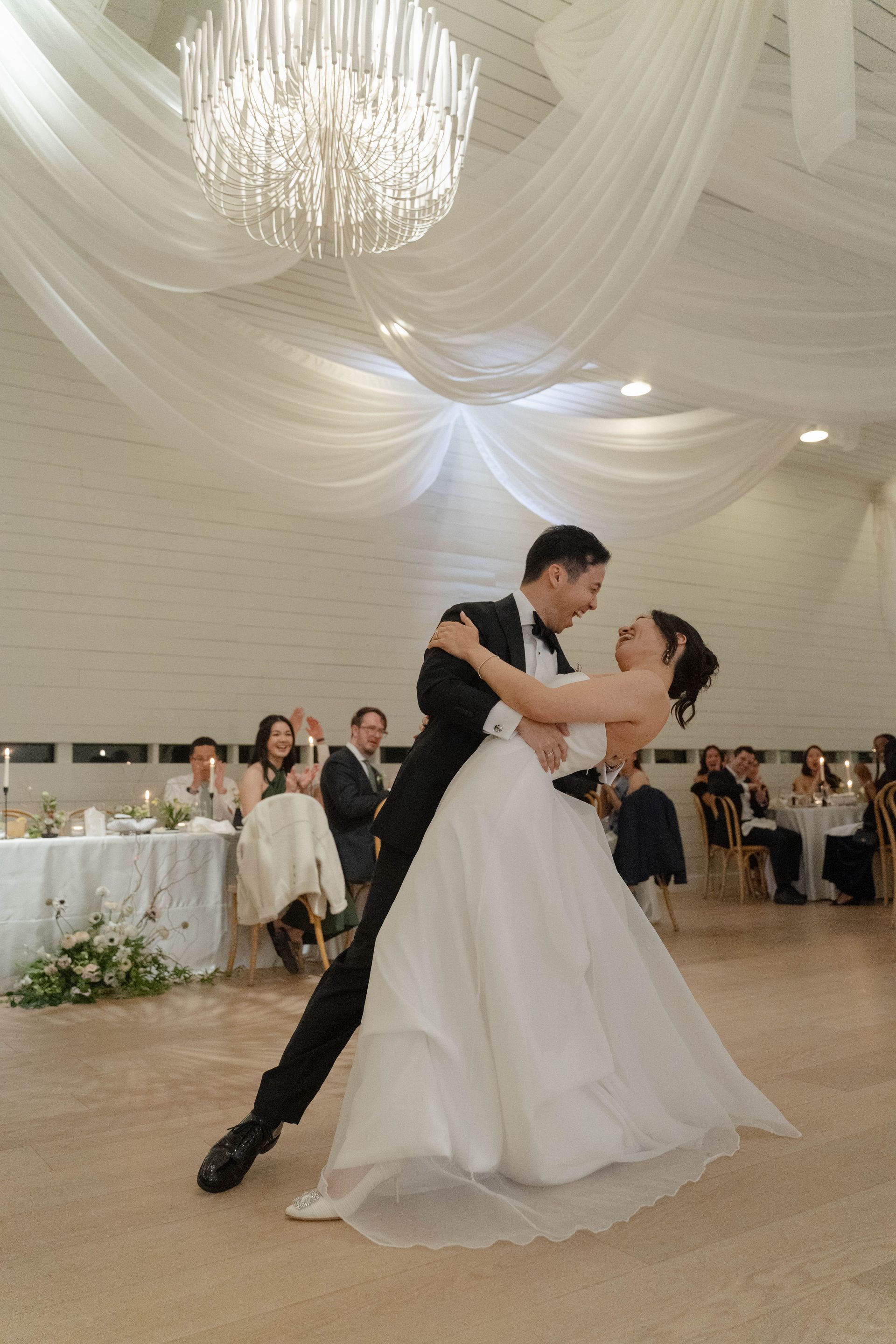 Bride and groom dancing under draped white ceiling in a wedding reception hall