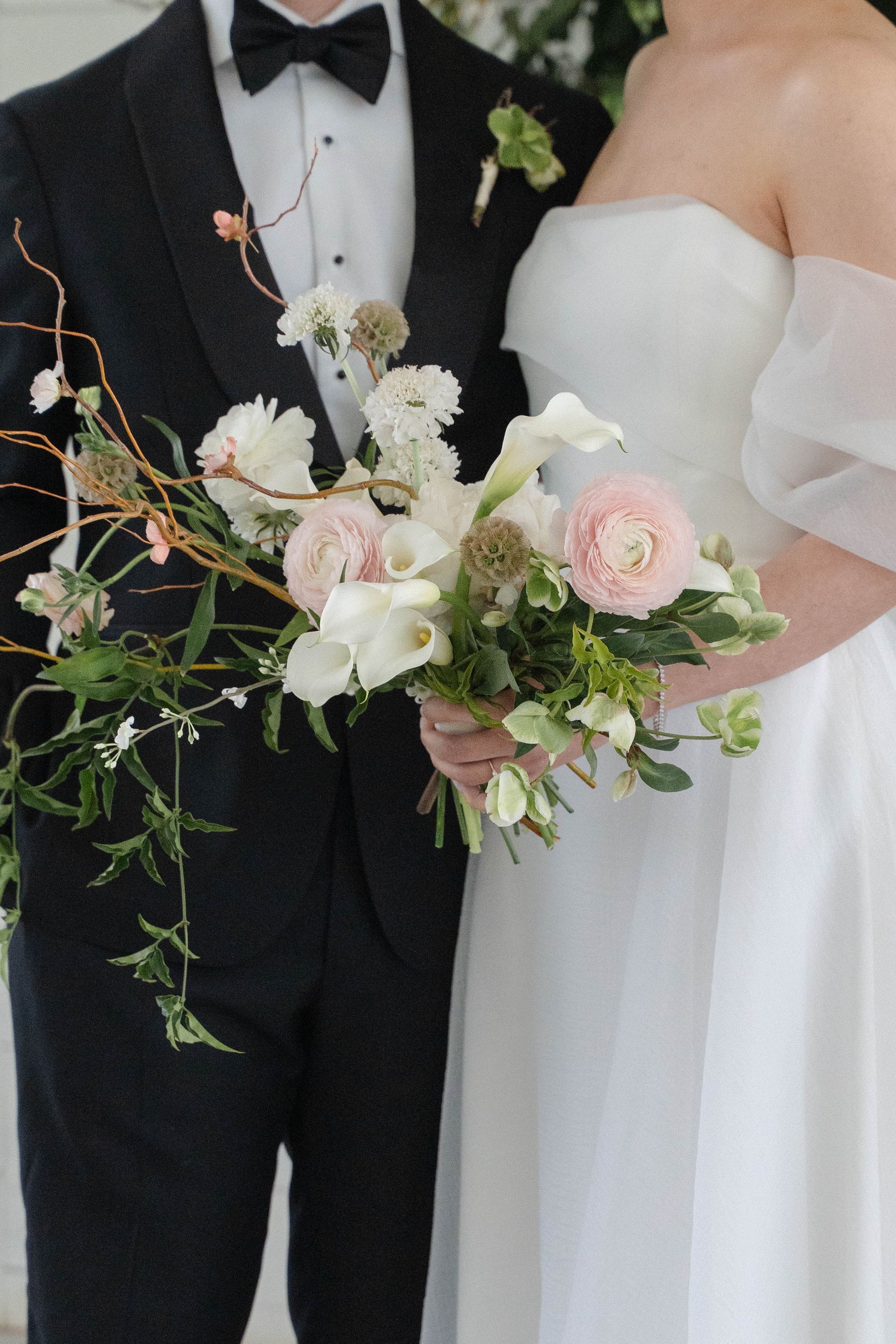 Bride and groom holding a bouquet of white and blush flowers at a wedding