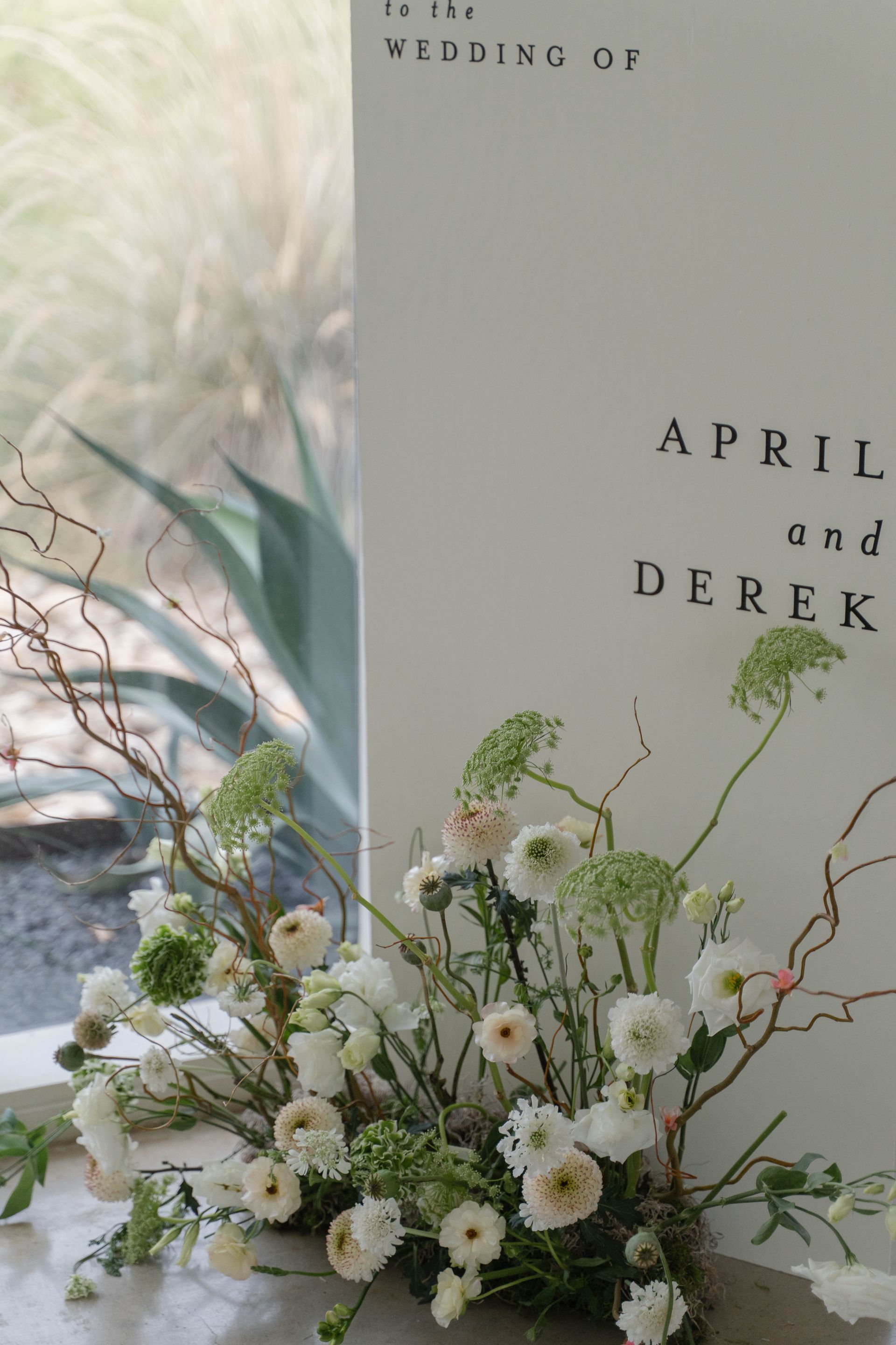 Wedding invitation with white floral arrangement and the names April and Derek