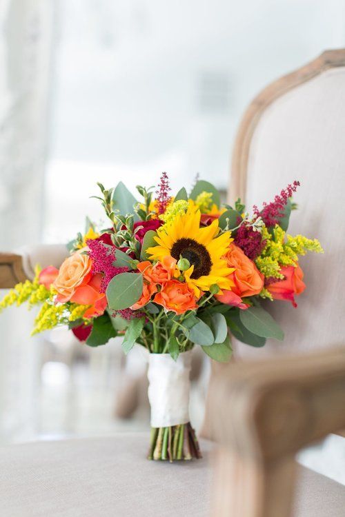 Bright bouquet of sunflowers, orange roses, and pink flowers in a vase on a table