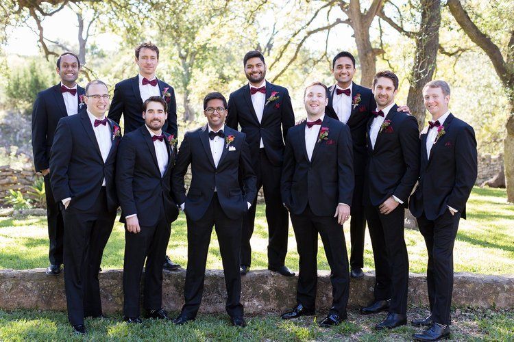 Group of formally dressed people standing outdoors in a park, posing for a photo.