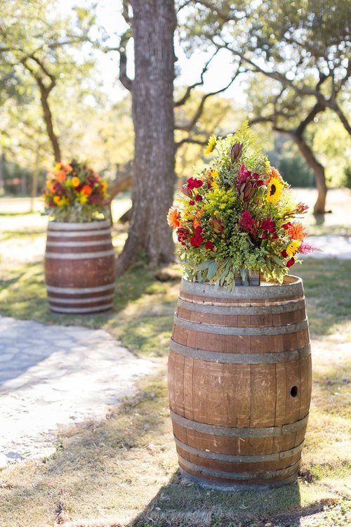 Flower bouquets in wooden barrels along a sunlit outdoor path