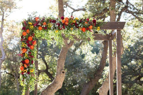 Flower-covered wooden arch in an outdoor garden with trees and sunlight