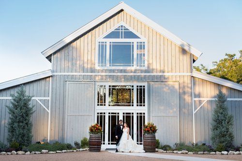 Bride and groom standing at the entrance of a white barn wedding venue