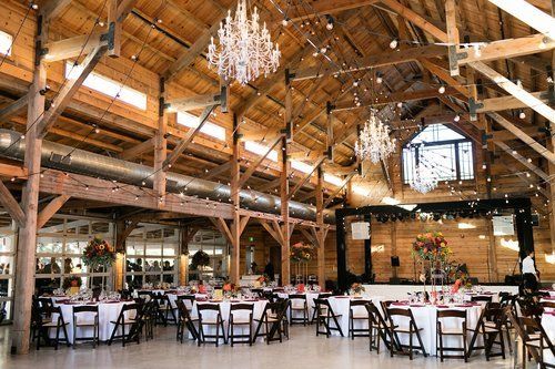 Spacious rustic hall with high wooden beams and tables set for a formal event or dining service