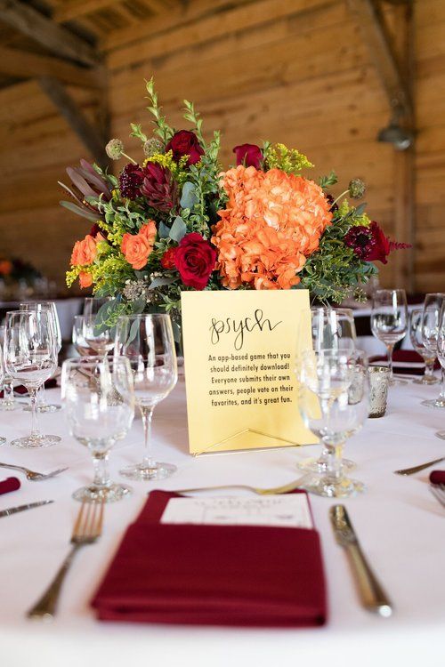 Floral centerpiece and place setting with burgundy napkin on a decorated reception table