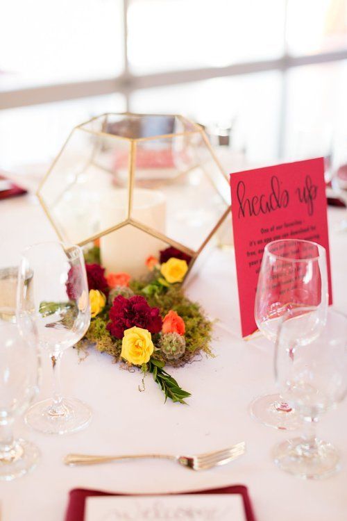 Elegant wedding table centerpiece with gold geometric terrarium, yellow and pink flowers, and a pink place card
