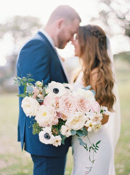 Couple embracing outdoors, holding a pale pink and white bouquet