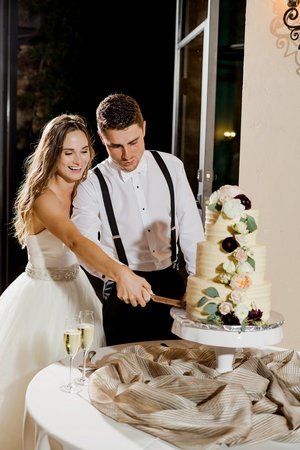 Bride and groom cut a decorated wedding cake at a reception table