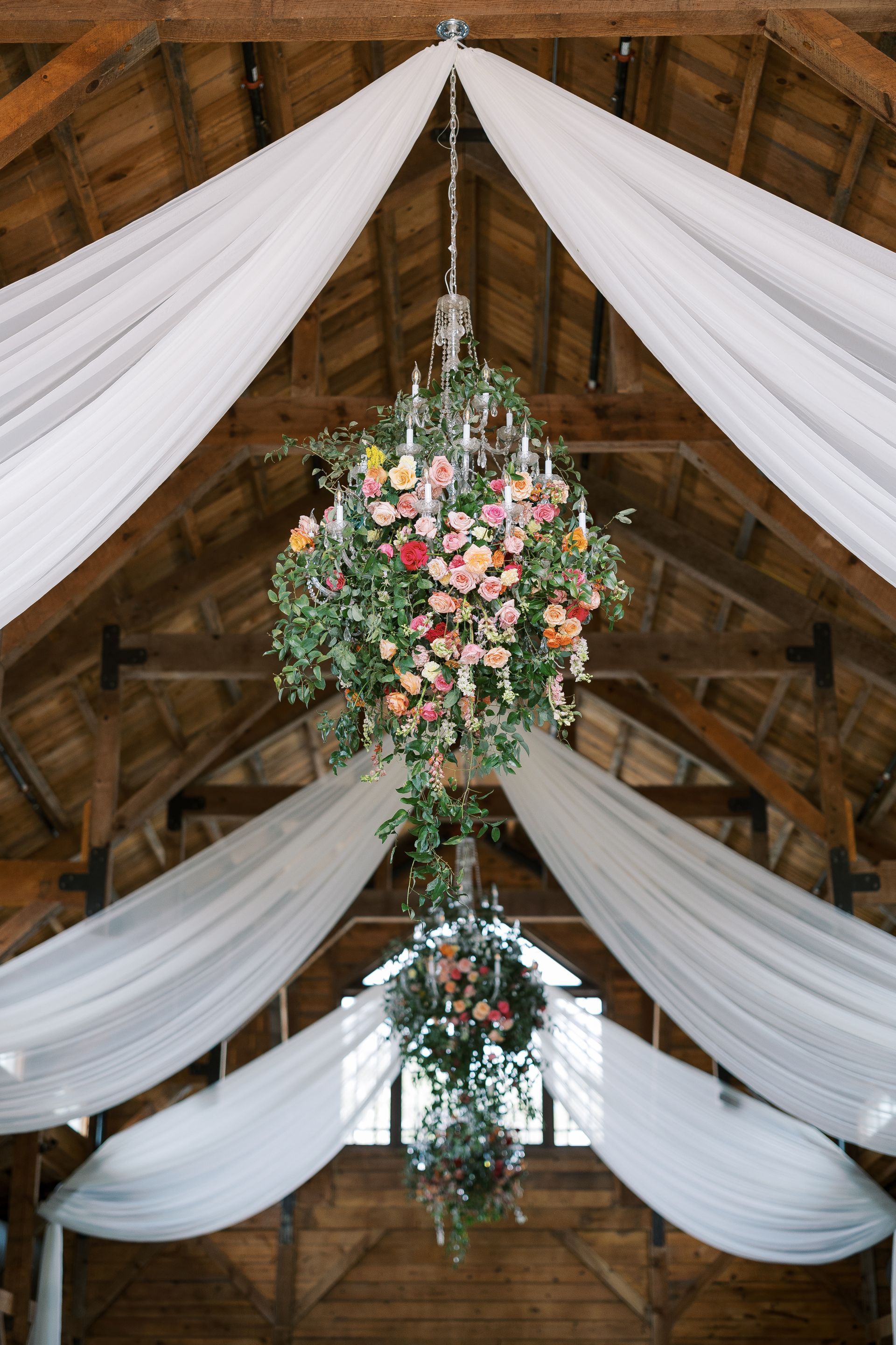 White draped wedding venue ceiling with hanging pink and green floral arrangements