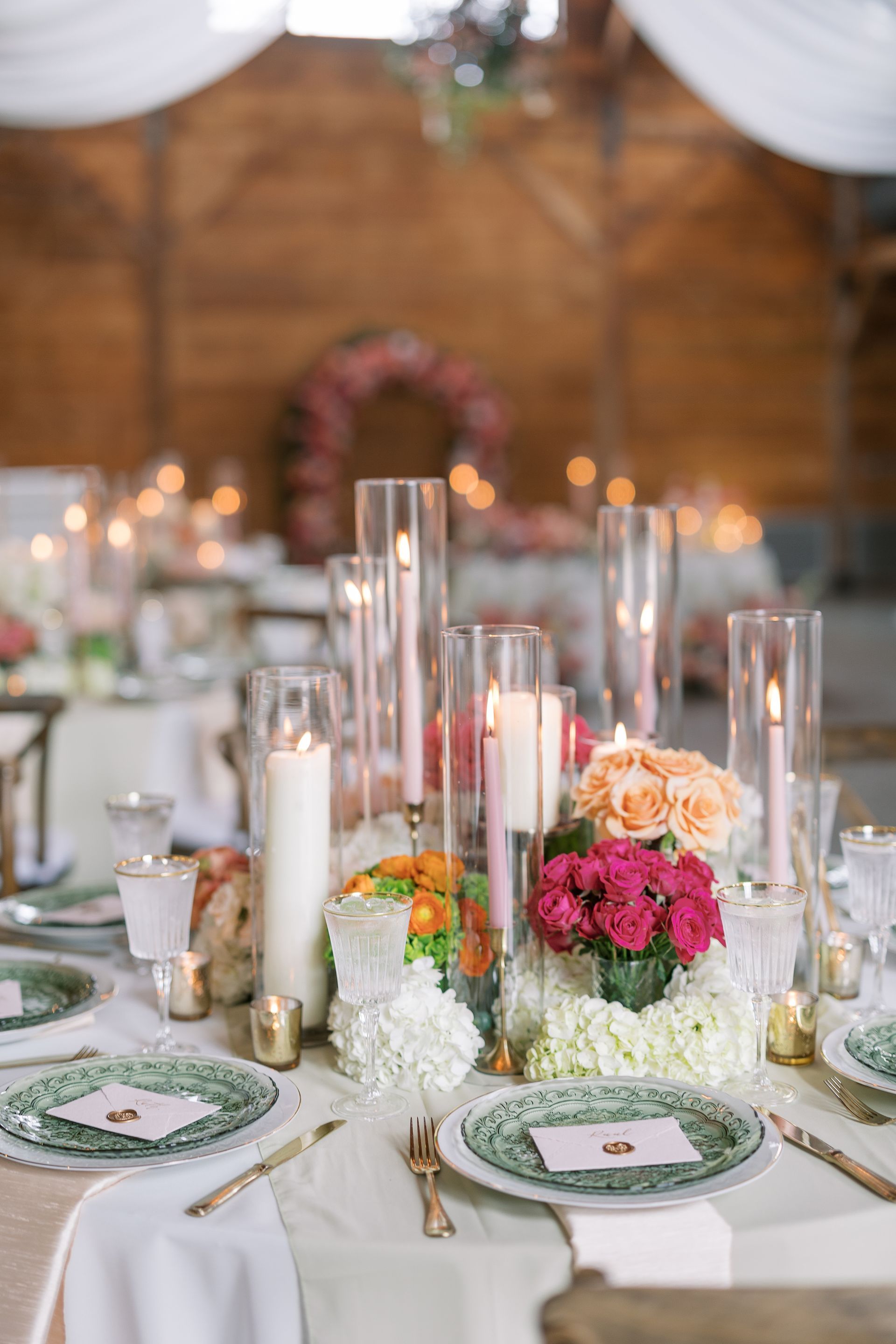 Elegant wedding reception table with white linens, tall candles, and peach and pink floral centerpiece