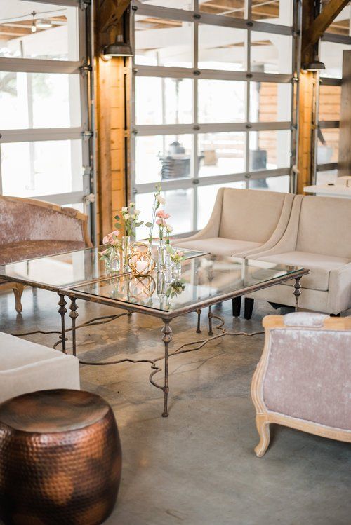 Modern lounge with beige sofas, glass coffee table, and large windows with warm wood beams.