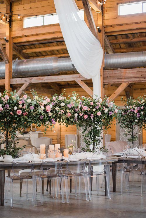 Elegant floral wedding reception table under draped white fabric in a rustic barn venue