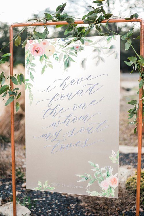 Floral wedding welcome sign on a copper frame with greenery and pastel flowers outdoors