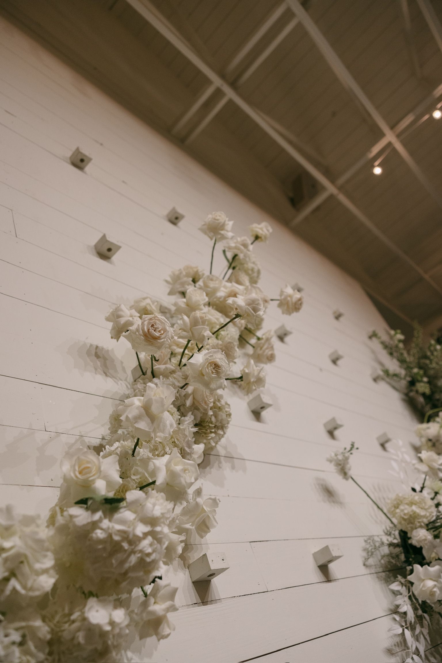 White floral arrangement on a wall in a softly lit indoor event space