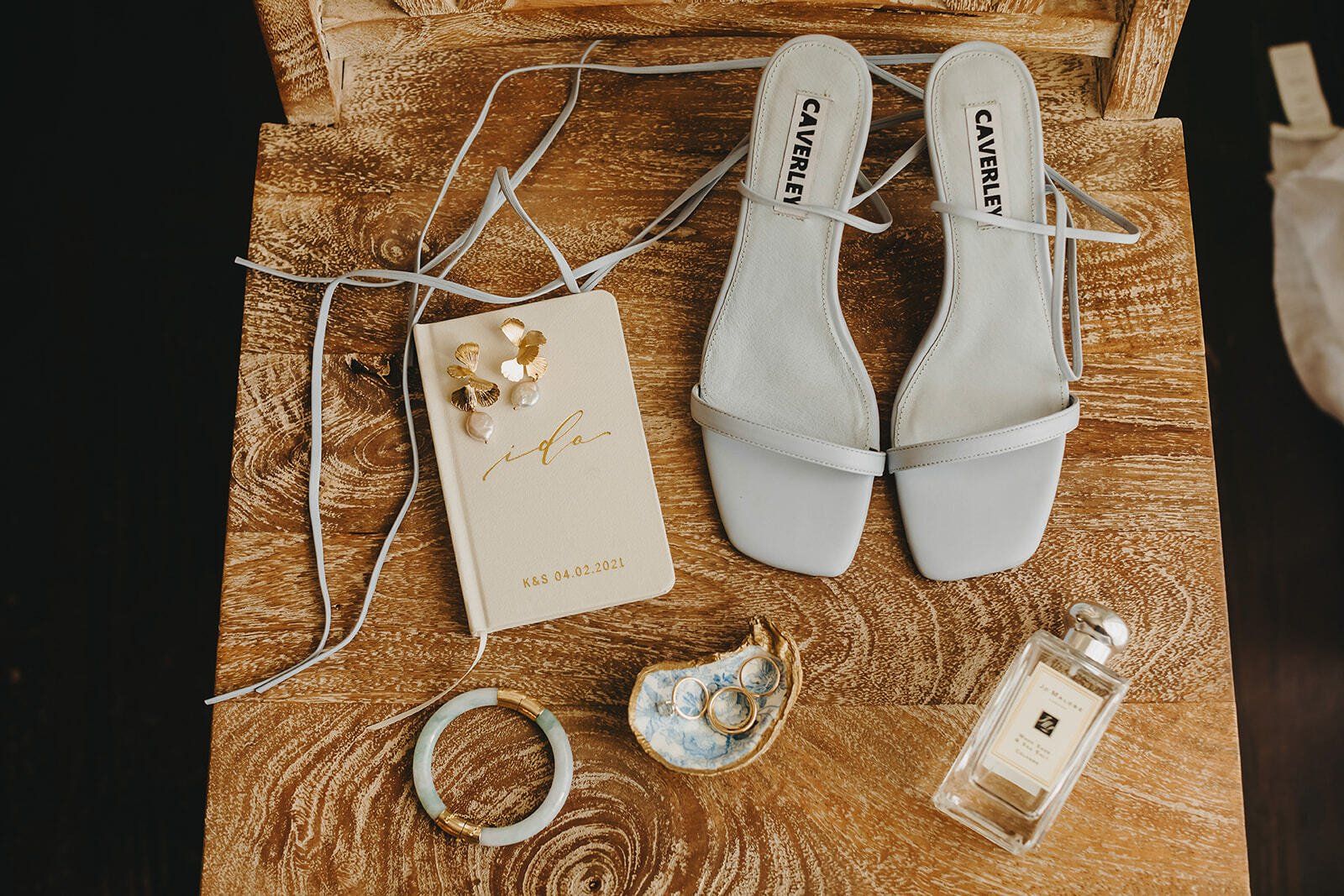 Silver heeled sandals with bridal accessories on a woven gold mat