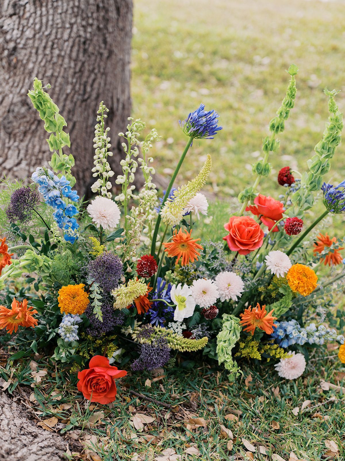 Colorful wildflower bouquet at the base of a tree in a grassy outdoor setting