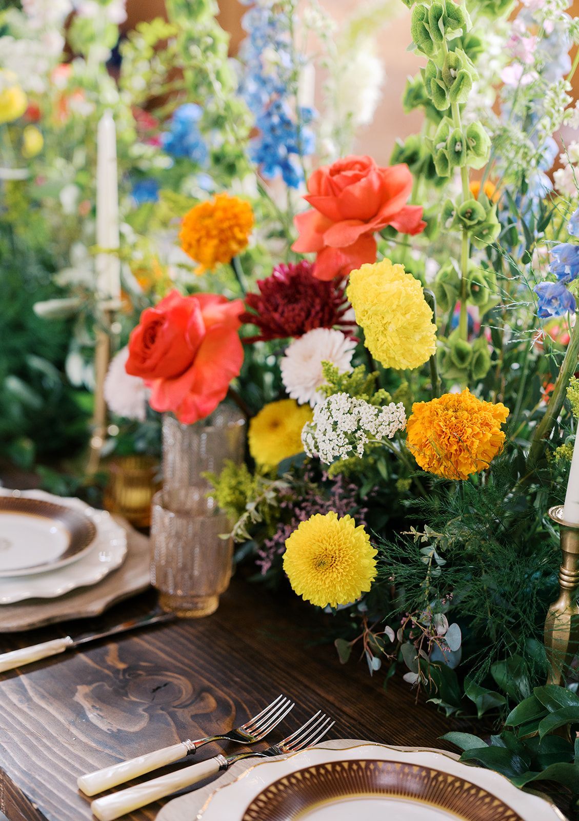 Colorful floral centerpiece with red, yellow, white, and orange blooms on a set dining table