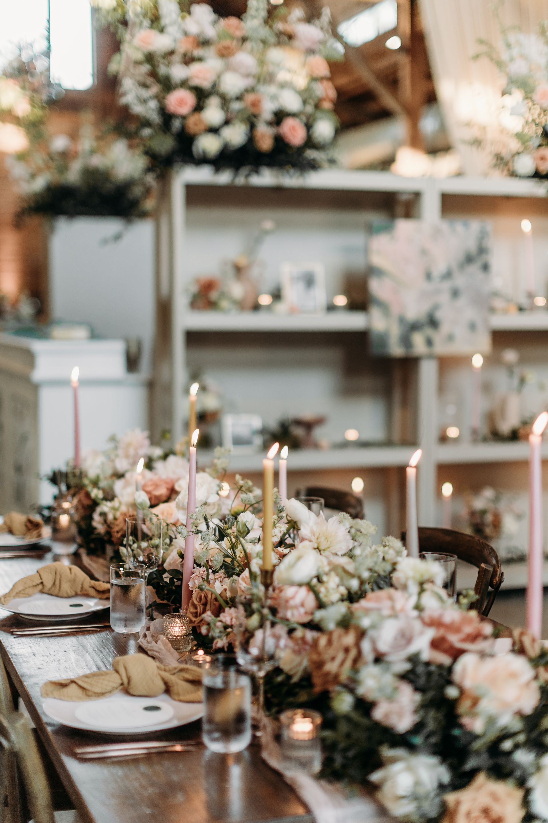 Elegant floral table setting with candles and blush roses in a softly lit room