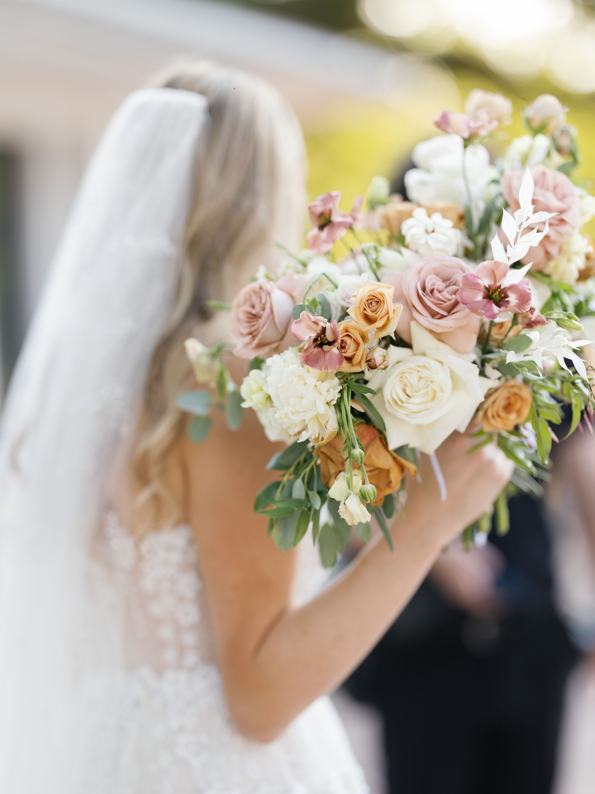 Bride holding a pastel flower bouquet at an outdoor wedding ceremony