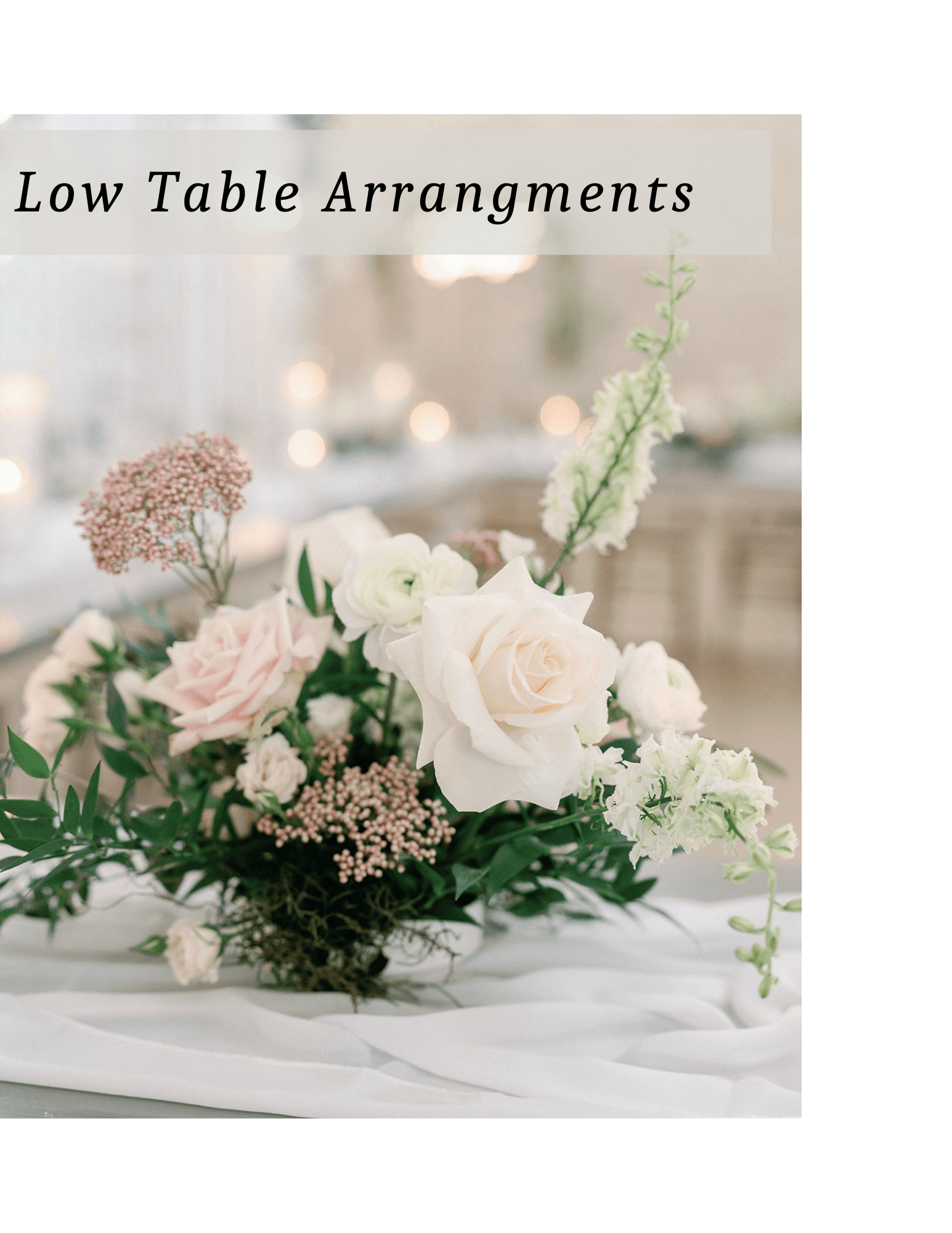 Elegant pastel low table floral centerpiece with roses and greenery on a white tablecloth