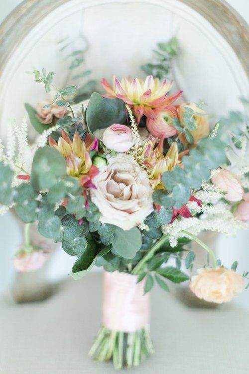 Pastel floral bouquet with roses and greenery in a glass vase against a soft background