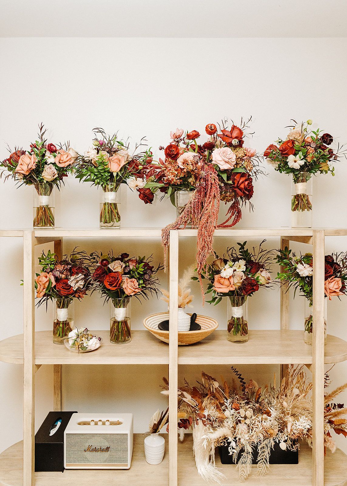 Shelves of colorful floral arrangements and dried bouquets in a bright room
