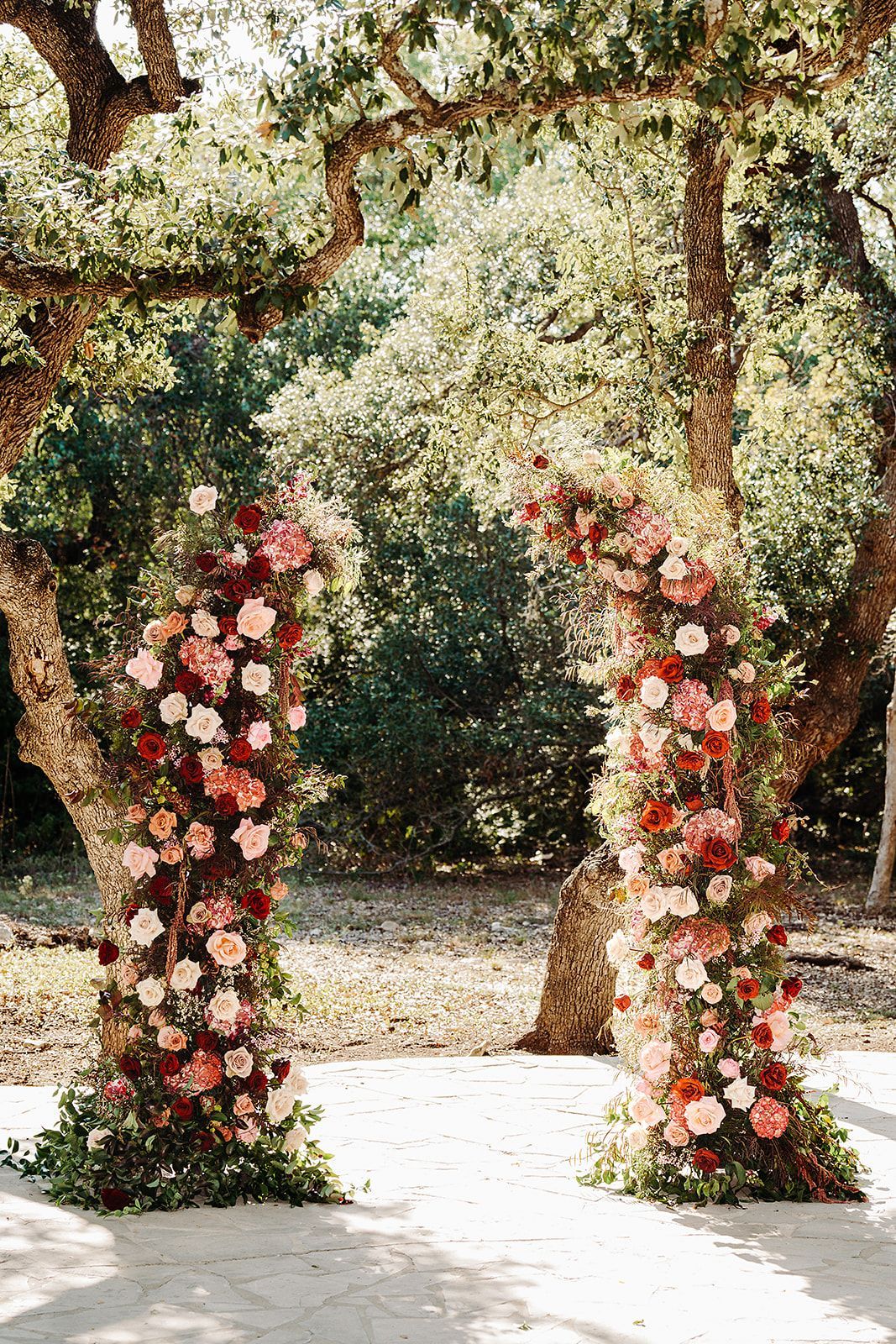 Flower-covered wedding arch in an outdoor garden under trees