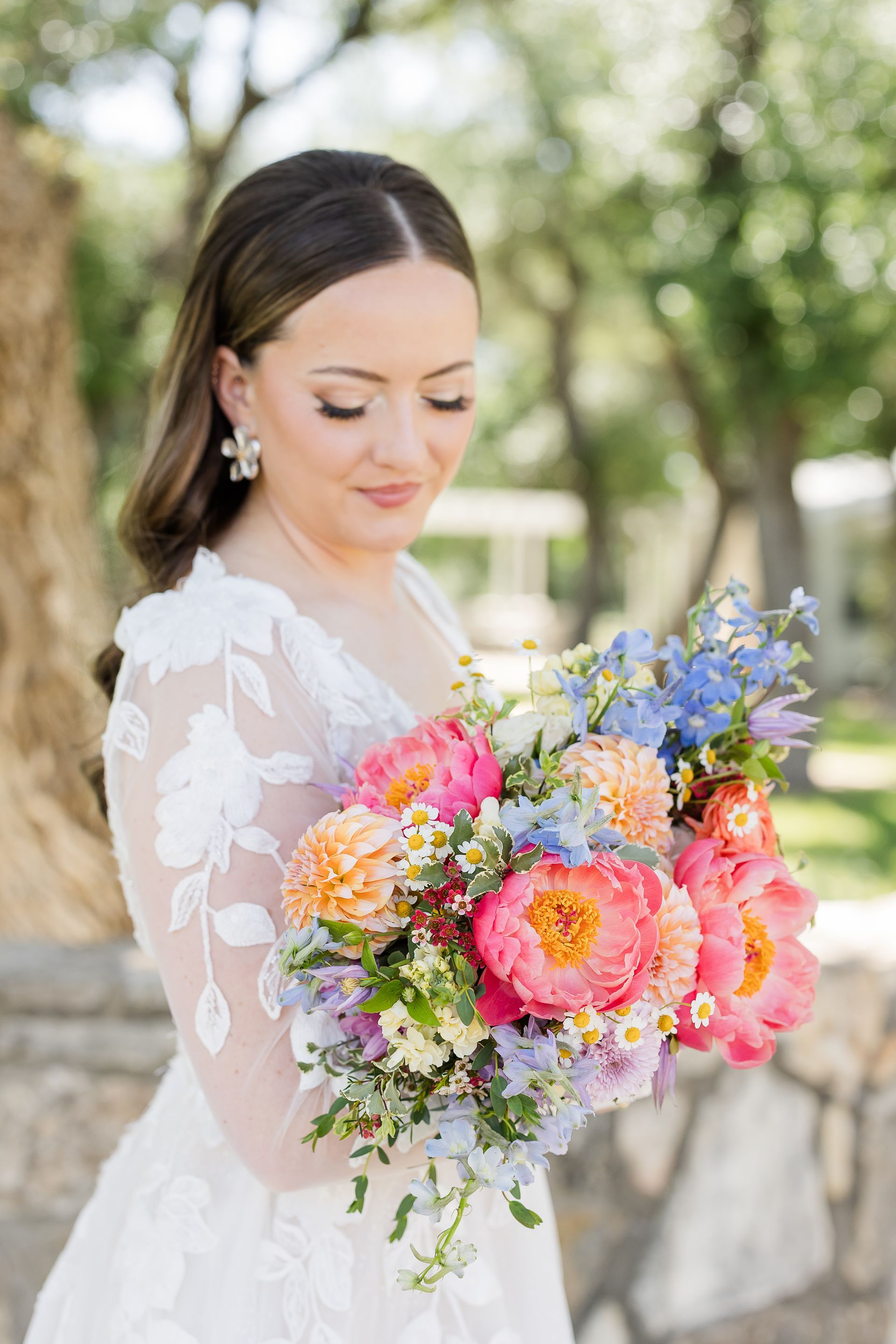 Woman holding a colorful bouquet of pink, purple, and yellow flowers outdoors