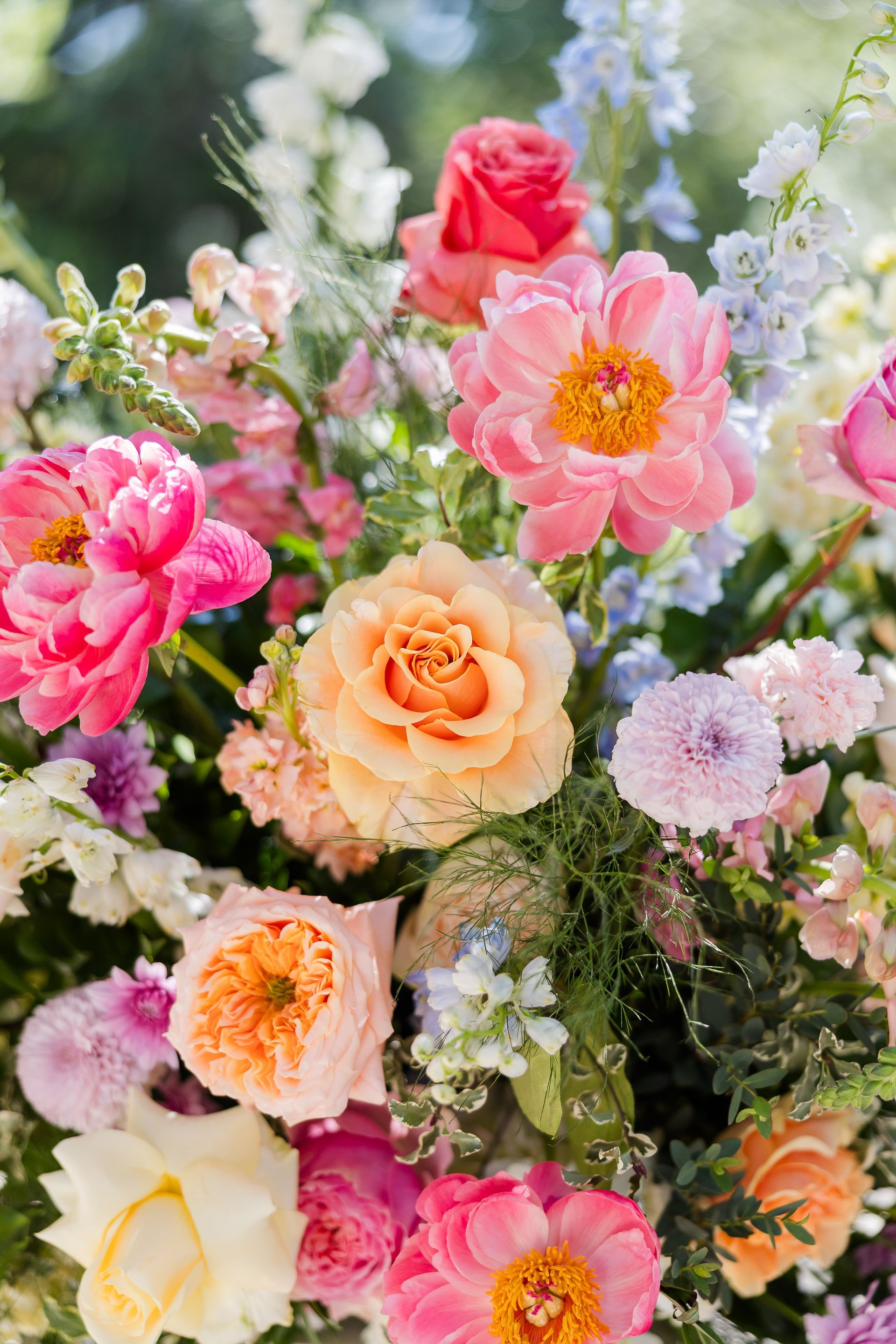 Colorful bouquet of roses, peonies, and delicate white flowers in pink, peach, and cream shades