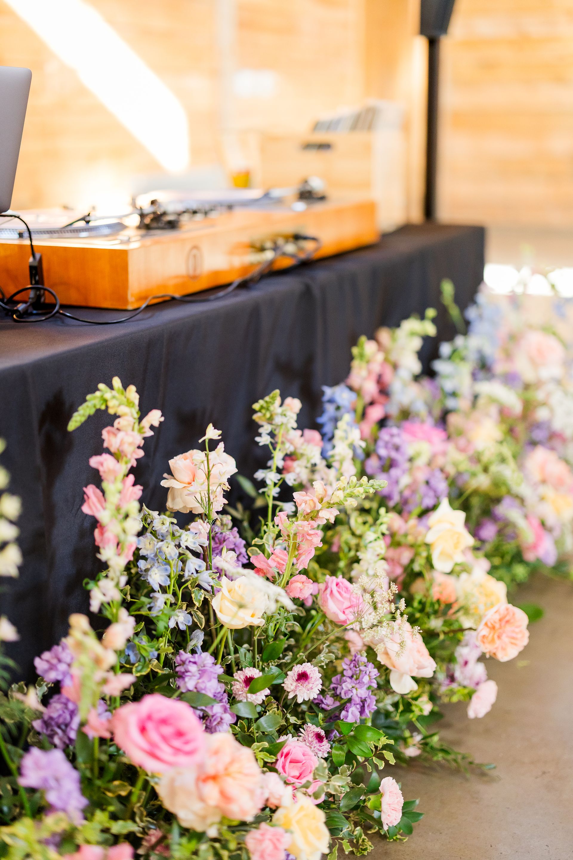 Flower arrangements beside a black-draped table with a wooden sound system in the background