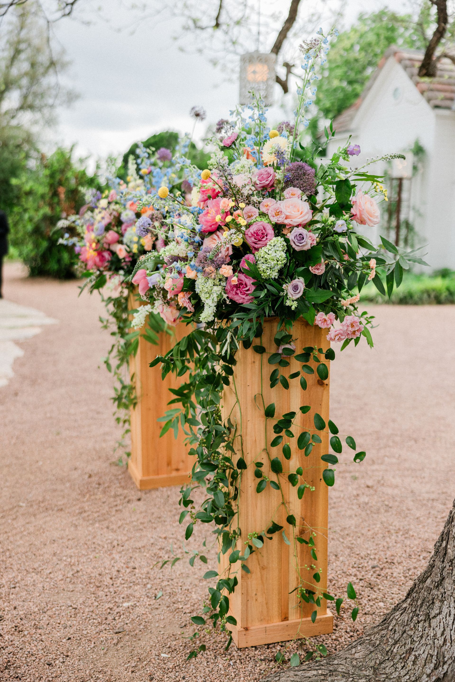 Wooden floral arrangement filled with pink, white, and purple flowers on a garden pathway