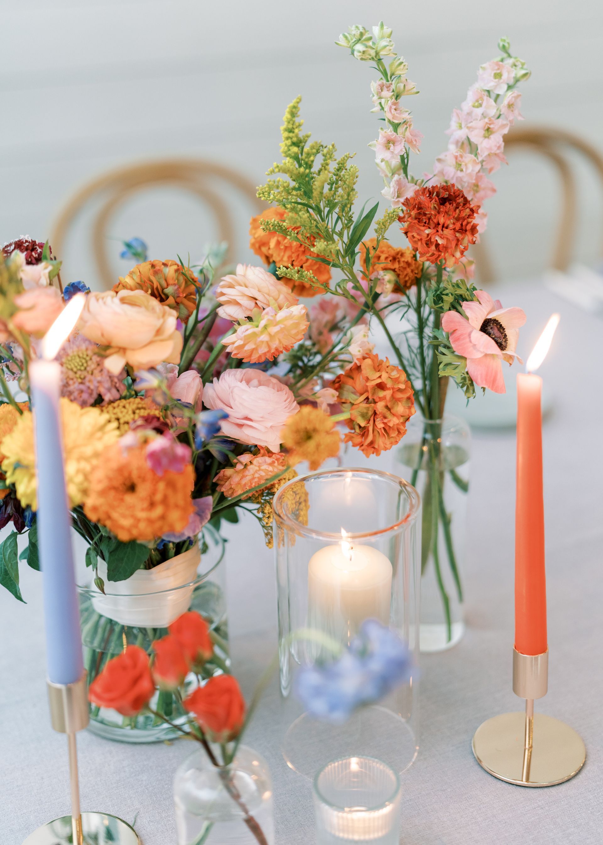 Floral centerpiece with pastel flowers and lit candles on a table setting