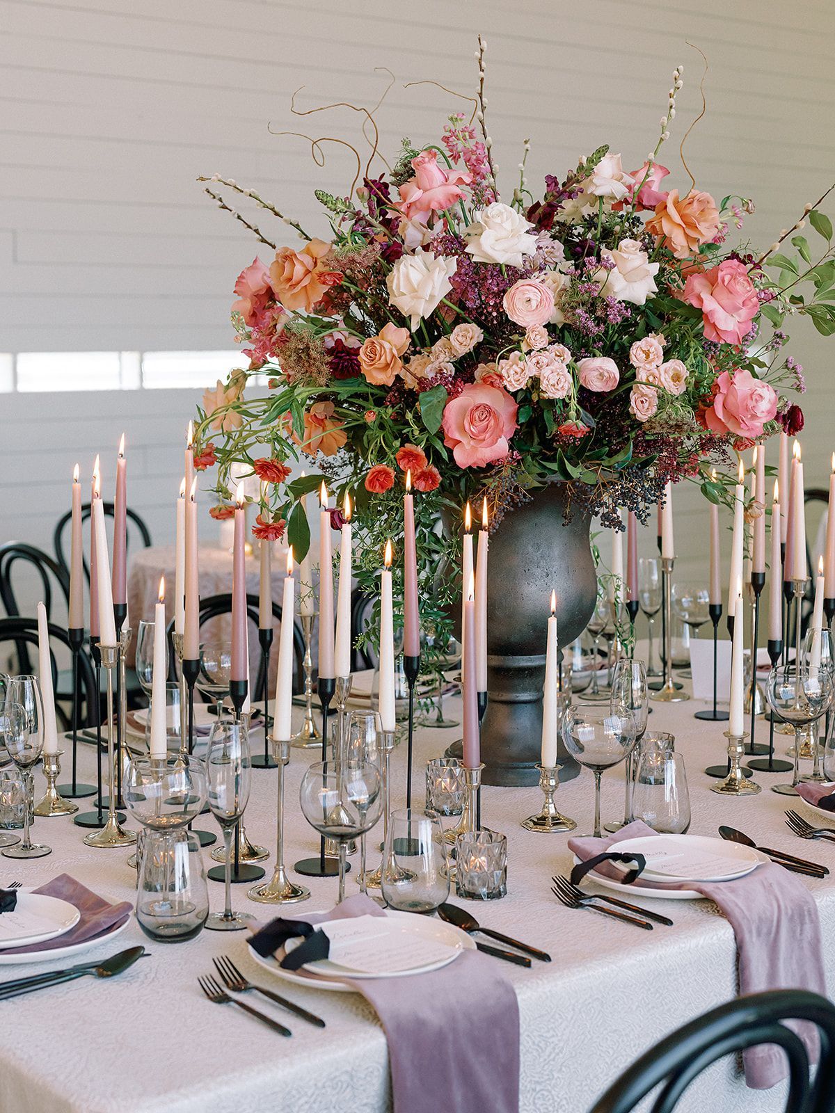 Elegant banquet table with pink floral centerpiece, glass candlesticks, and white place settings