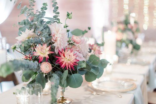 Floral centerpiece with pink and white flowers on a decorated dining table at a reception