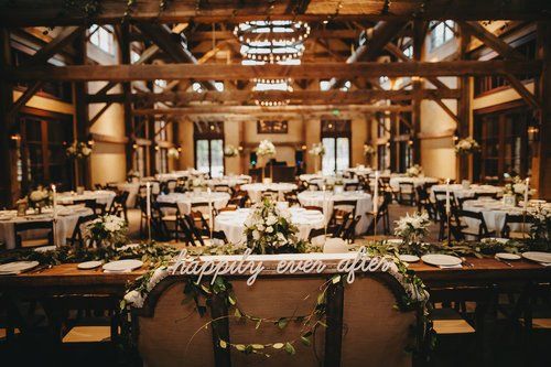 Rustic wedding reception venue with long tables, string lights, and wooden beams