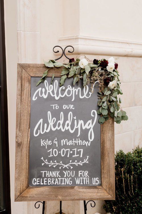 Wedding welcome sign with flowers and handwritten text in a wooden frame