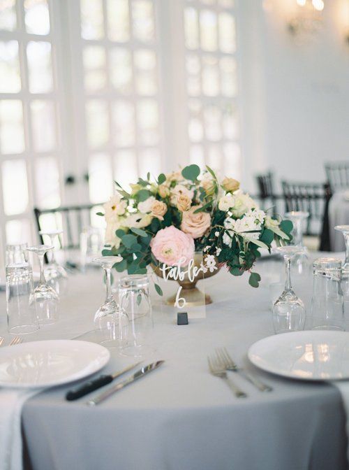 Elegant banquet table with white linens and a pastel floral centerpiece in a bright reception hall