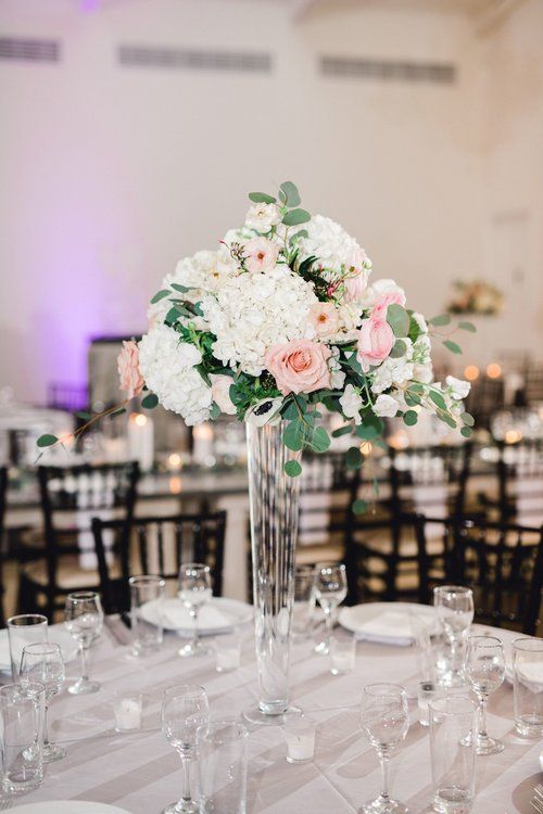 Elegant wedding reception table centerpiece with white and blush floral arrangement in a banquet hall