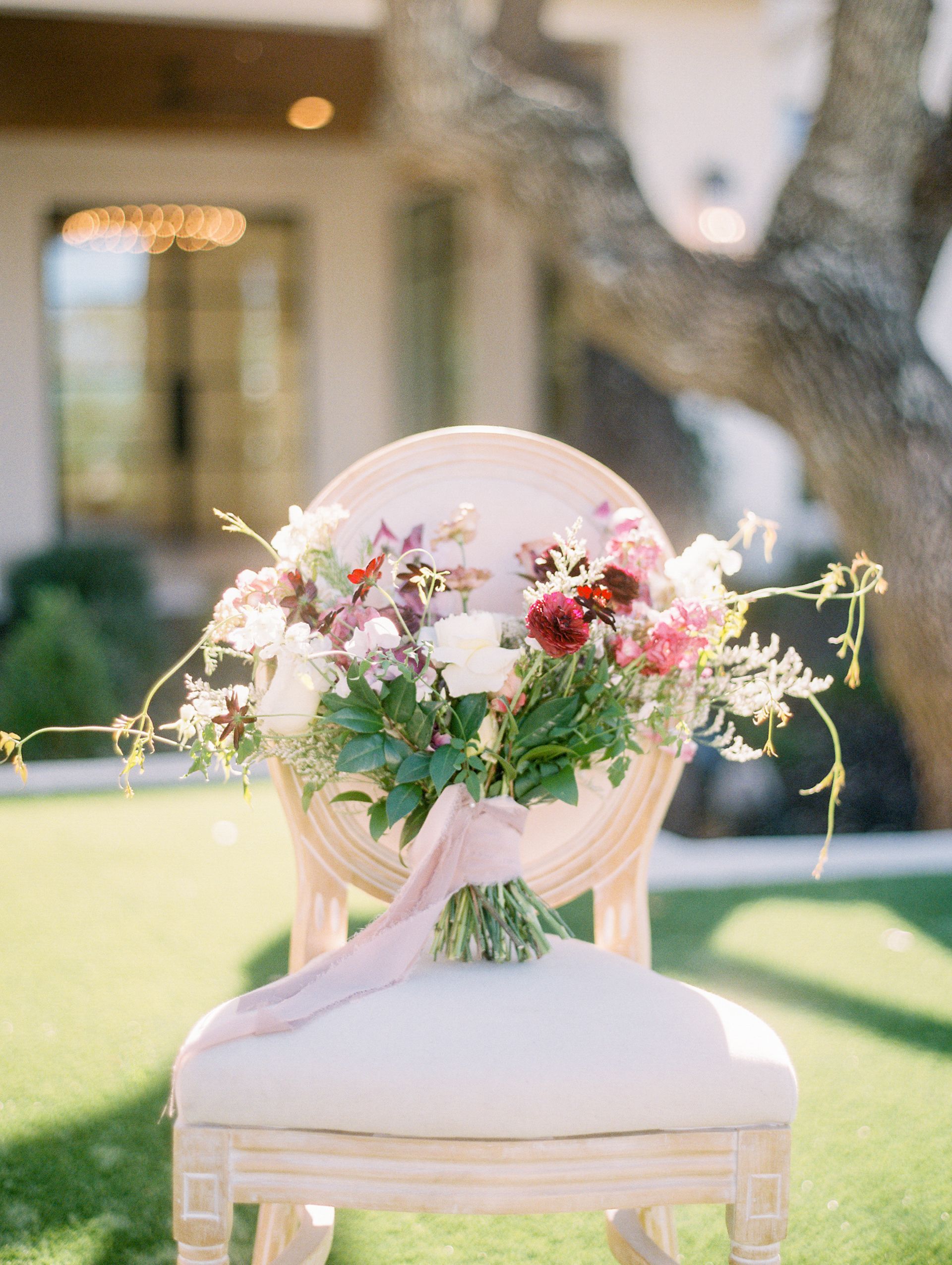 Floral bouquet on a white chair with pink draping in an outdoor garden setting