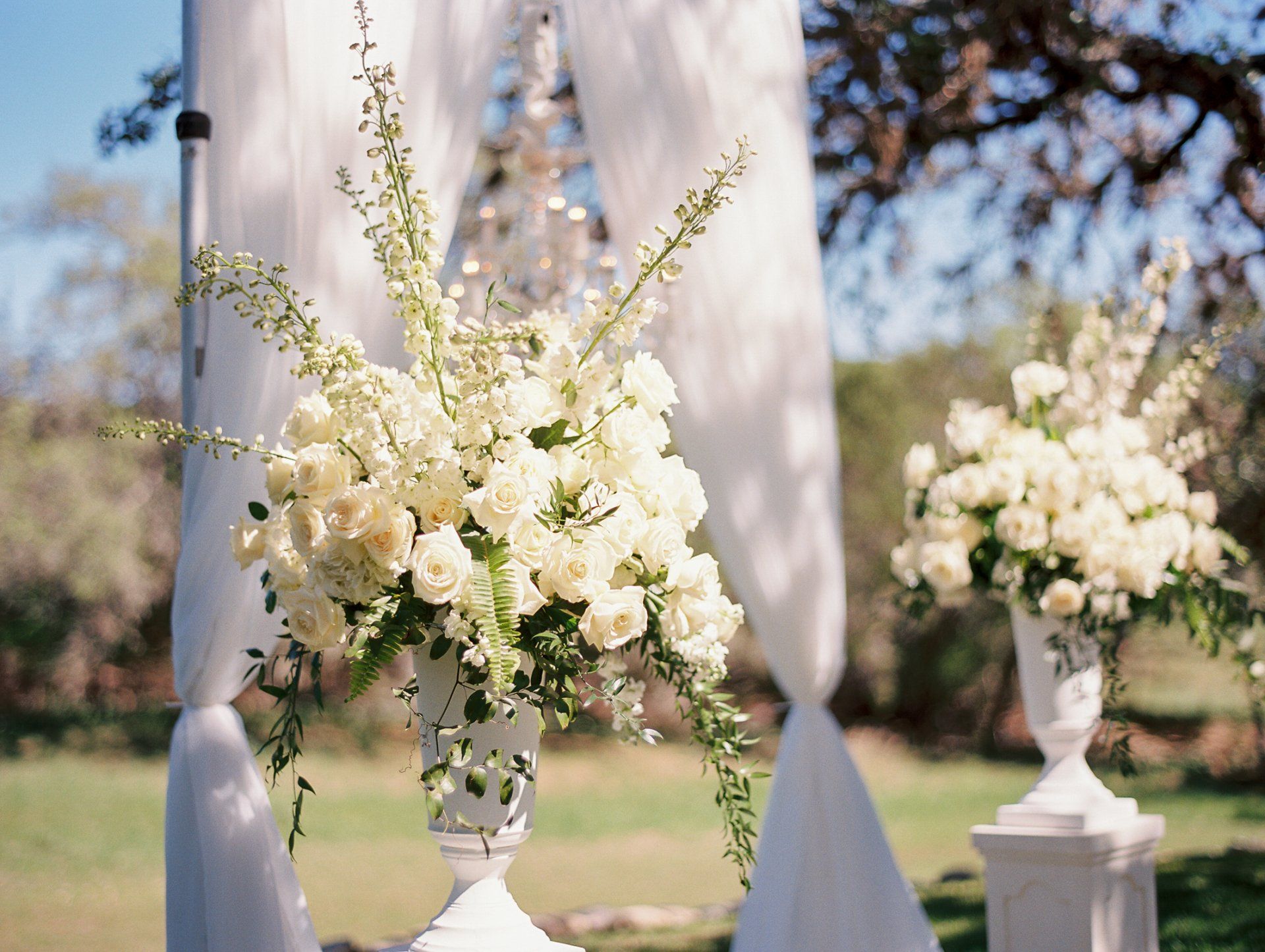 White floral arrangements on pedestals at an outdoor wedding venue