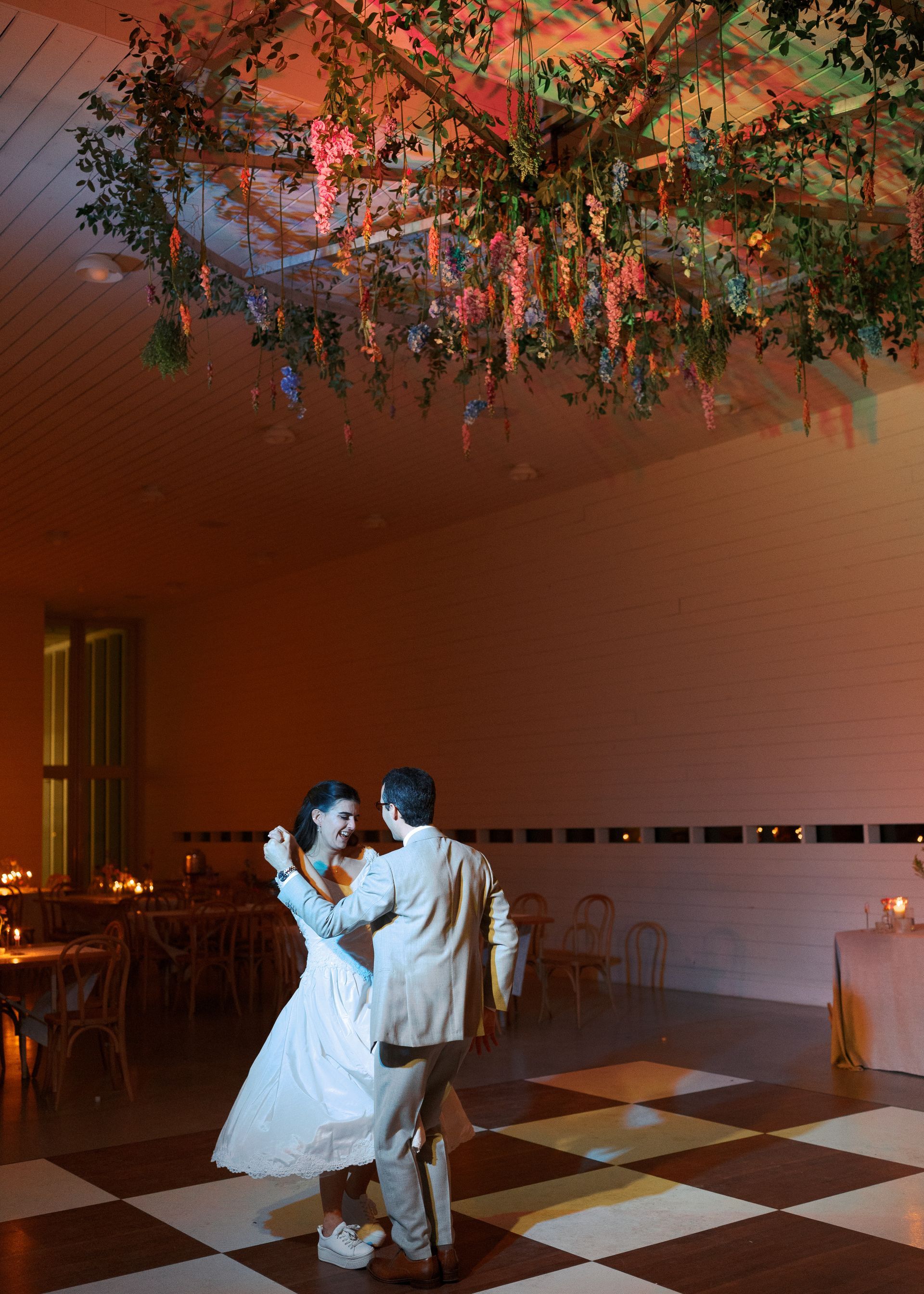 Couple dancing in a warmly lit hall beneath a floral ceiling decoration
