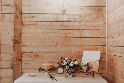 Rustic wooden backdrop with a table of flowers, jars, and a white board in a warm-toned room