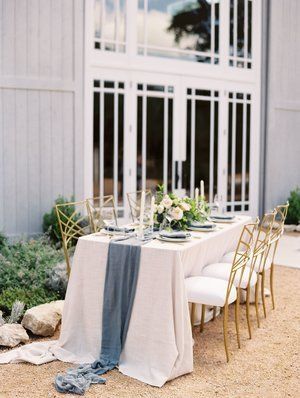 Elegant outdoor dining table with white and blue linens set beside a modern white building