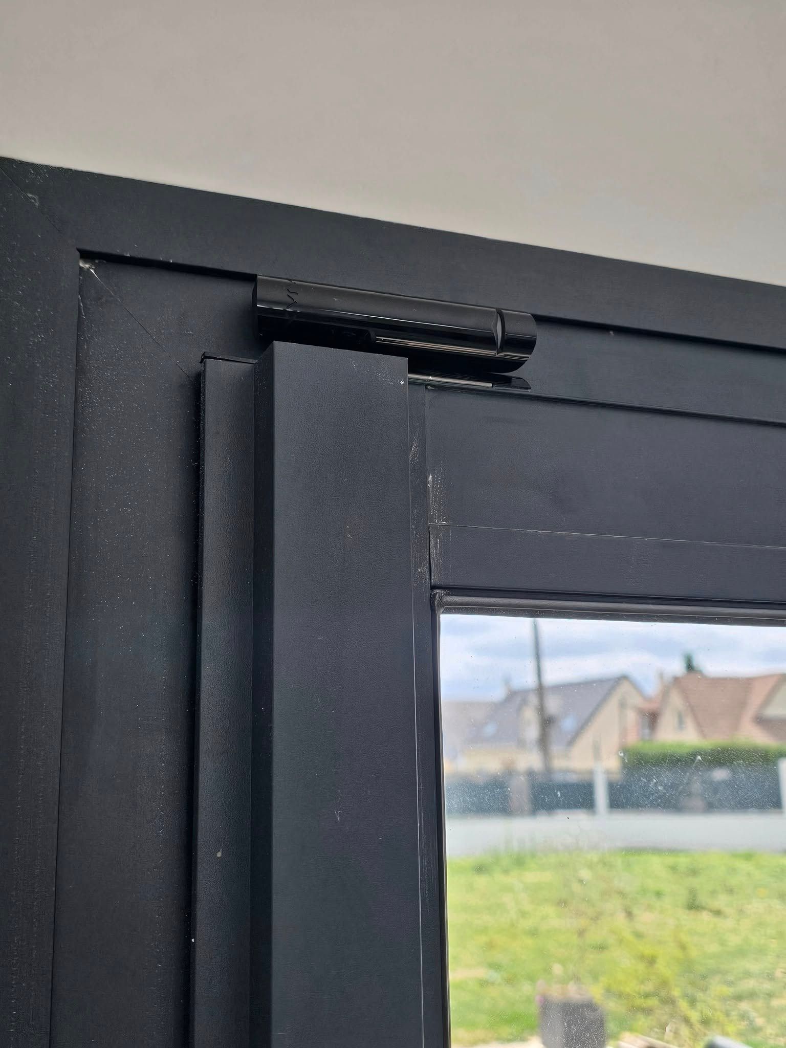 Un gros plan d'une fenêtre noire avec vue sur un champ.