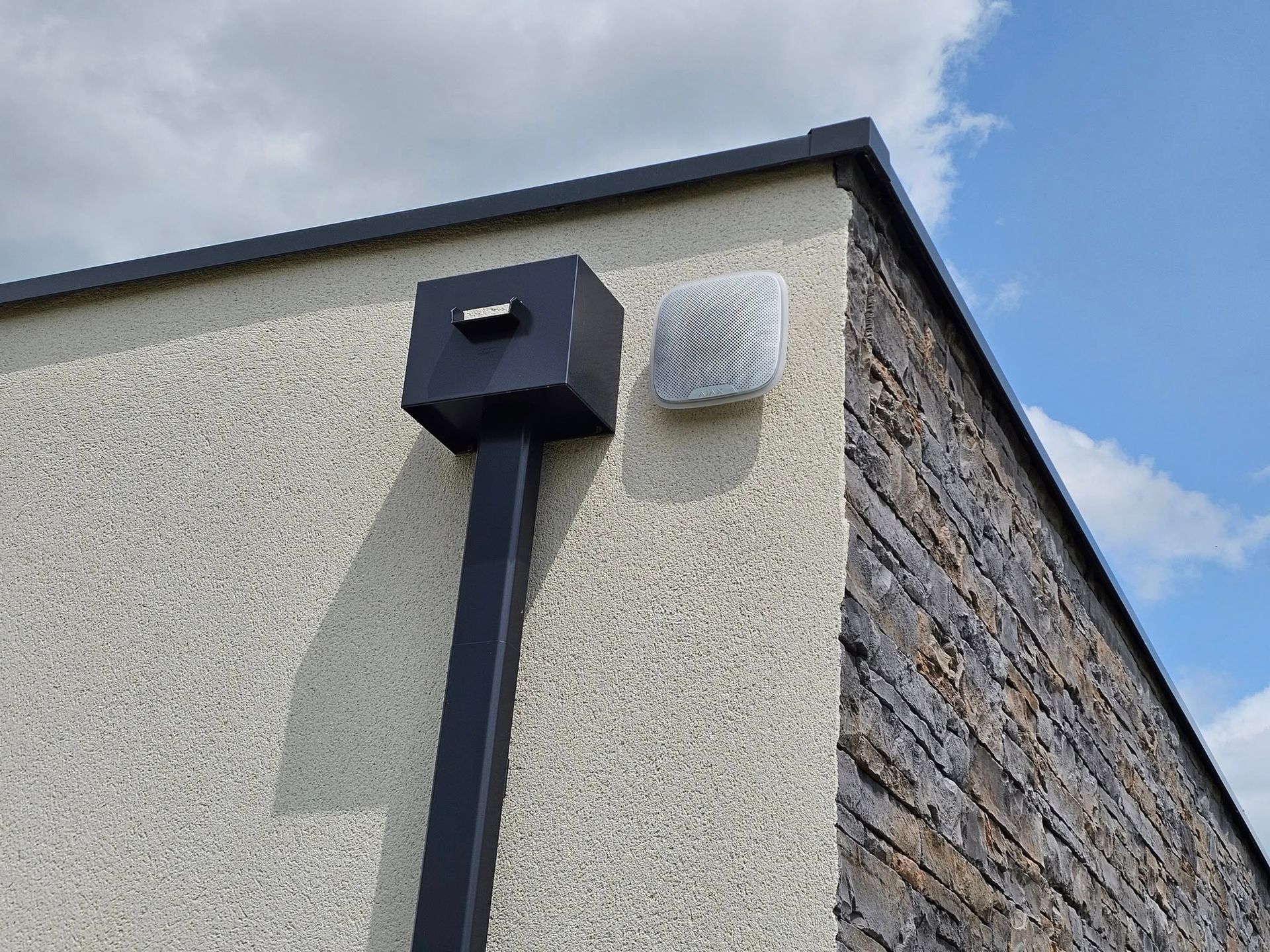 Un tuyau noir est fixé sur le côté d'un bâtiment.