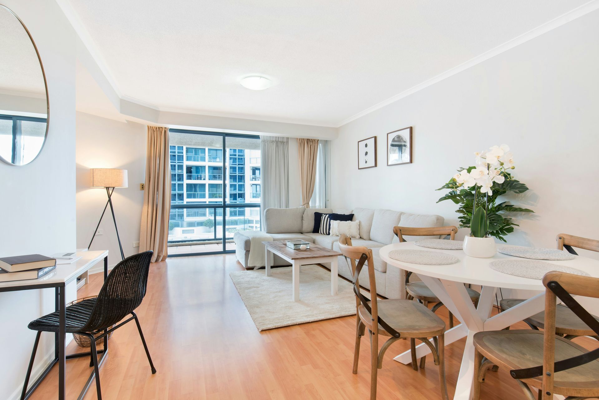 Bright modern apartment living room with dining table, sofa, balcony doors, and large windows